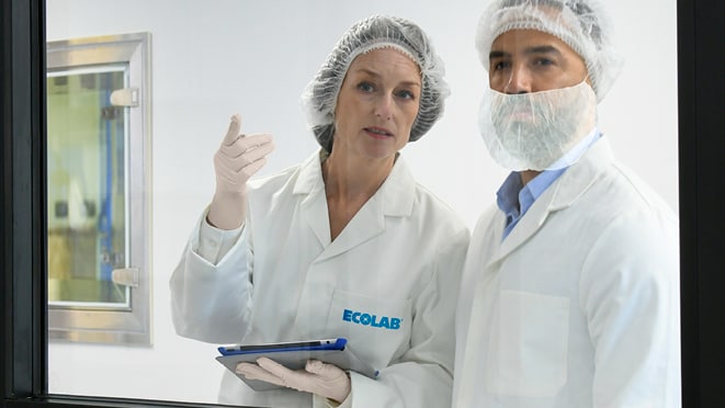 Two technicians looking at something in a cleanroom