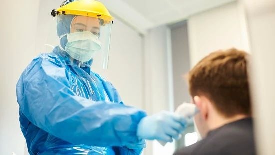 Nurse in PPE taking patients temp