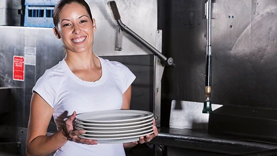 Person Holding Stack of Plates in Commercial Kitchen