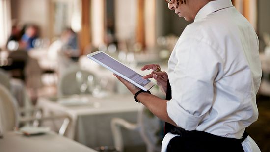 restaurant server working on a tablet in the front of house